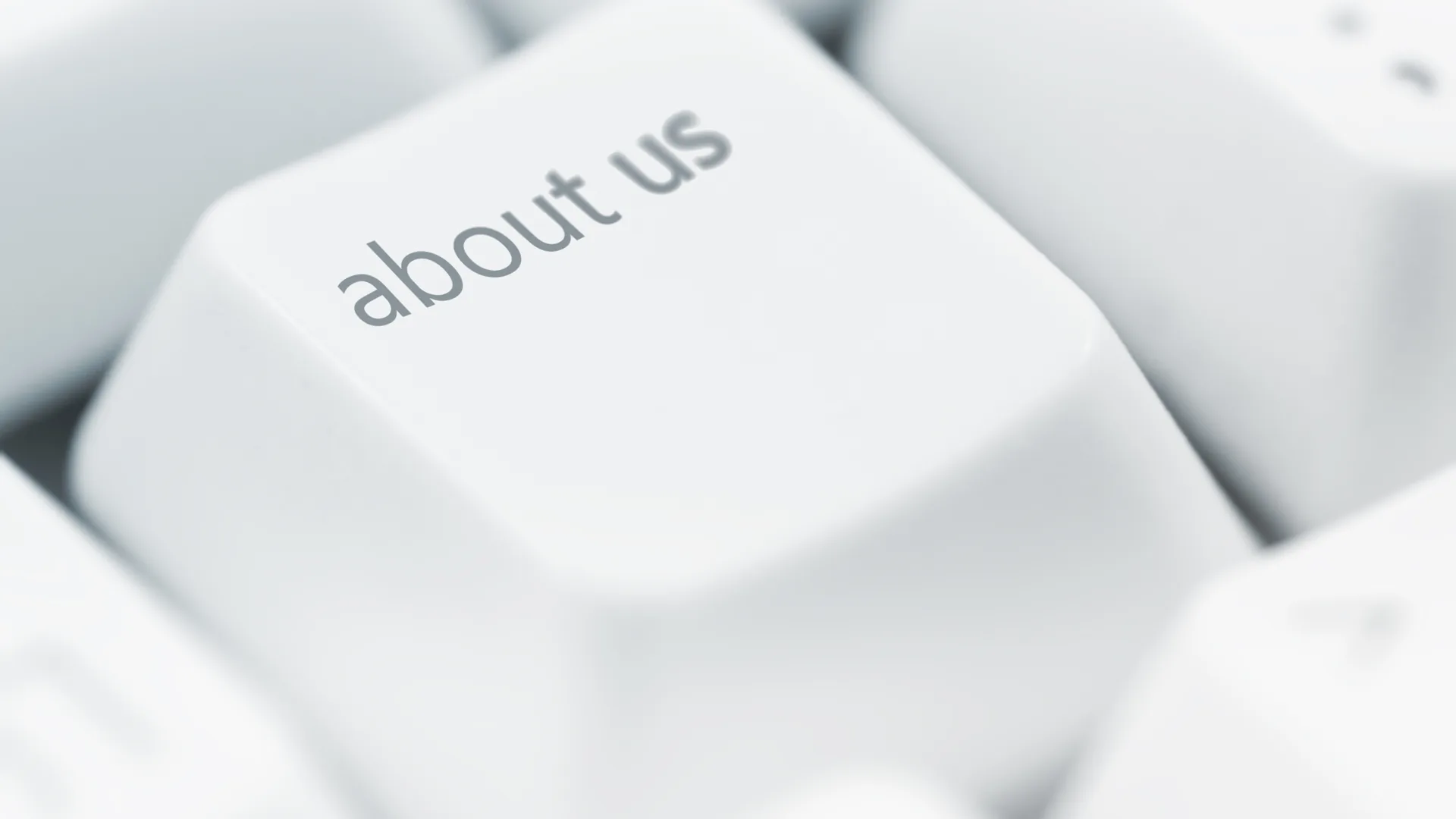 Nahaufnahme einer weißen Tastatur mit einer Taste, auf der „about us“ steht